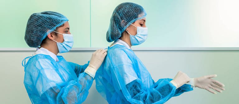 Krankenschwester hilft Arzt in OP-Kleidung im Krankenhaus, Symbolfoto Pflegeberufe (Foto: IMAGO, IMAGO / Westend61)