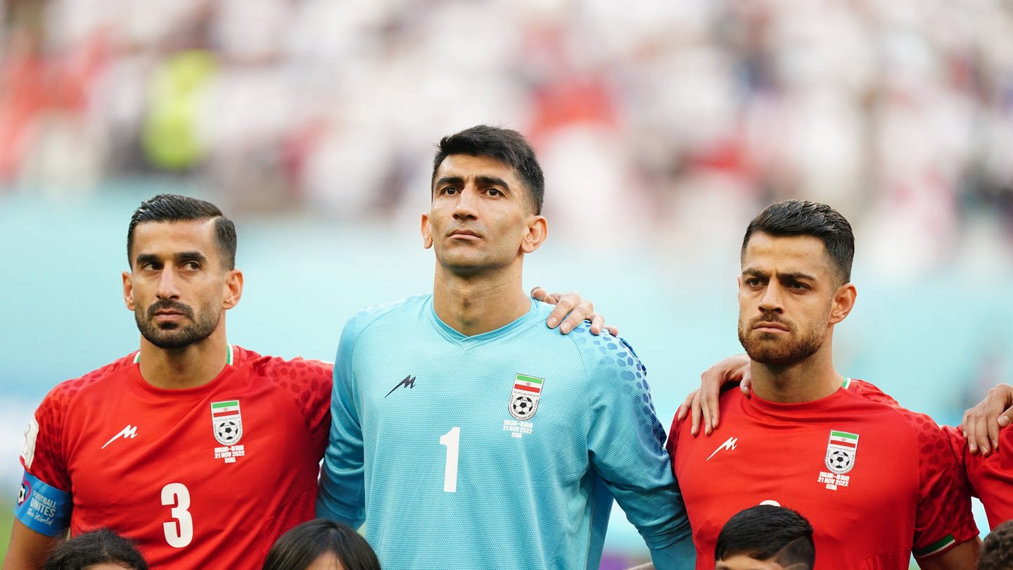 Fußball, WM 2022 in Katar, England - Iran, Vorrunde, Gruppe B, Chalifa International Stadion, Irans Ehsan Hajisafi (l-r), Torwart Alireza Beiranvand und Morteza Pouraliganji stehen vor dem Spiel nebeneinander.