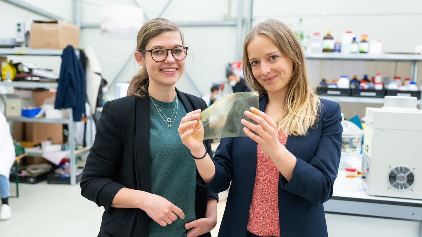 Johanna Baare (l) und Anne Lamp von Traceless Materials zeigen eine Folie aus abbaubaren Materialen. (Foto: picture-alliance / Reportdienste, picture alliance/dpa | Philipp Schulze)