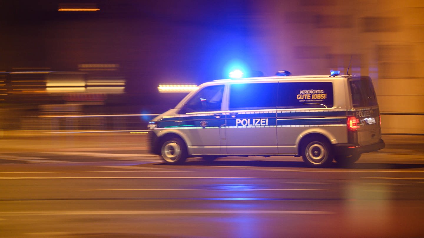 Ein Polizeiwagen mit Blaulicht fährt am Silvesterabend durch die Innenstadt zu einem Einsatz (Symbolbild)