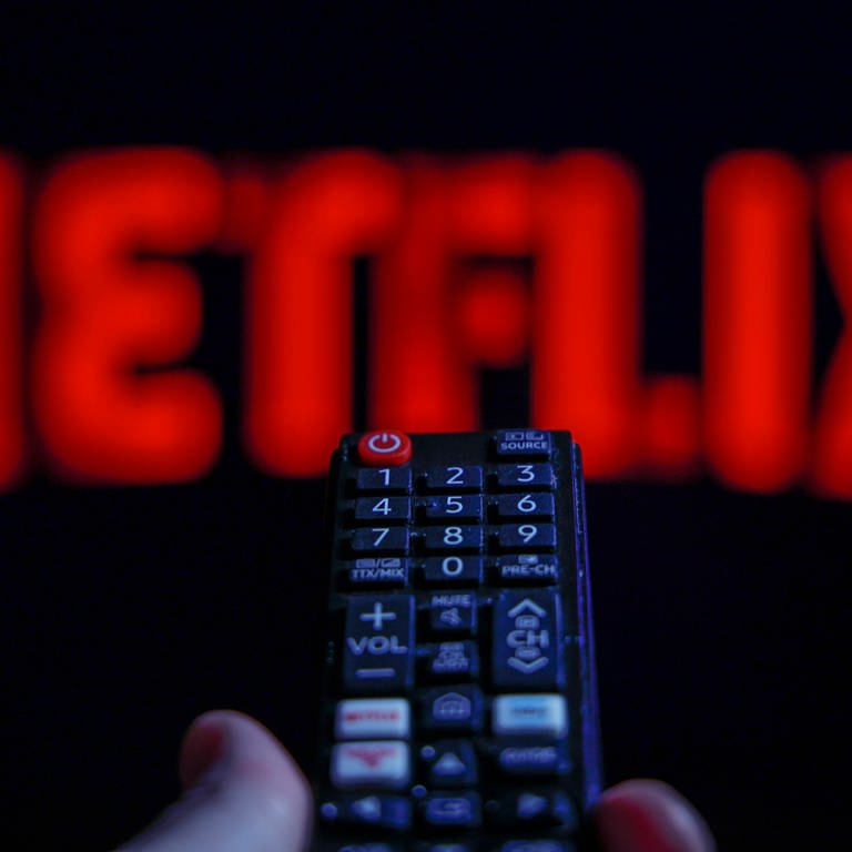 Social Media-Illustrationen Das Netflix-Logo ist auf einem Fernseher im Hintergrund, eine Fernbedienung im Vordergrund zu sehen (Foto: IMAGO, IMAGO / NurPhoto)