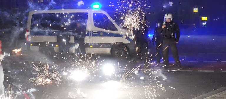 Polizeibeamte stehen hinter explodierendem Feuerwerk. (Foto: dpa Bildfunk, picture alliance/dpa/TNN | Julius-Christian Schreiner)