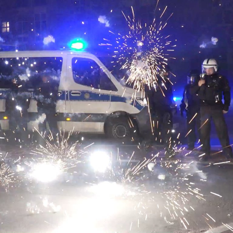 Polizeibeamte stehen hinter explodierendem Feuerwerk. (Foto: dpa Bildfunk, picture alliance/dpa/TNN | Julius-Christian Schreiner)