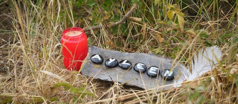 Eine Kerze und eine Tafel mit dem Namen Ayleen liegt am Ufer des Teufelsee im hessischen Wetteraukreis, in dem die Leiche der 14-jährigen Ayleen gefunden wurde. (Foto: dpa Bildfunk, picture alliance/dpa | Frank Rumpenhorst)