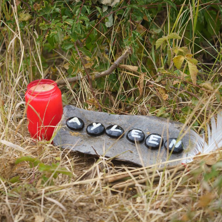 Eine Kerze und eine Tafel mit dem Namen Ayleen liegt am Ufer des Teufelsee im hessischen Wetteraukreis, in dem die Leiche der 14-jährigen Ayleen gefunden wurde. (Foto: dpa Bildfunk, picture alliance/dpa | Frank Rumpenhorst)