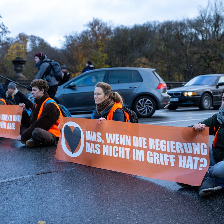 Klimaaktivisten der Umweltschutzbewegung «Letzte Generation» sitzen auf der Prinzregentenstraße und blockieren den Verkehr. (Foto: dpa Bildfunk, picture alliance/dpa | Lennart Preiss)