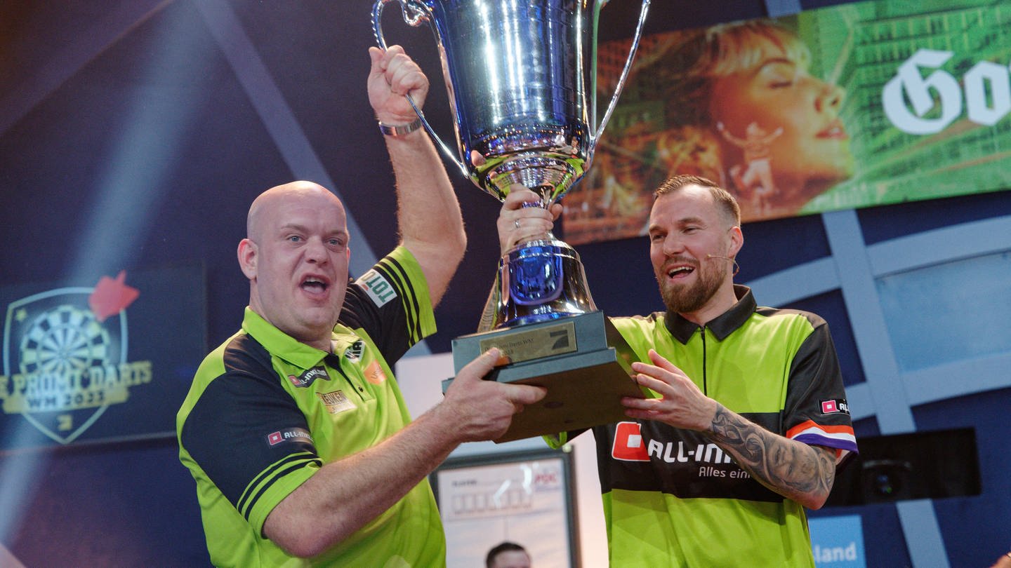 Der Fußballer Kevin Großkreutz und der Dartprofi Michael van Gerwen halten nach ihrem Sieg bei der Promi-Darts-WM einen großen Pokal gemeinsam hoch.