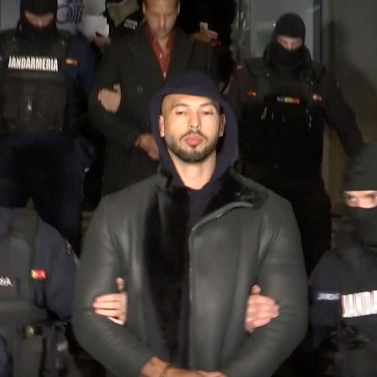 HANDOUT - Dieses Videostandbild des Fernsehsenders Observator Antena 1 zeigt Andrew Tate (M) bei seiner Festnahme durch die rumänische Polizei.  (Foto: dpa Bildfunk, picture alliance/dpa/Observator Antena 1 via AP | Uncredited)