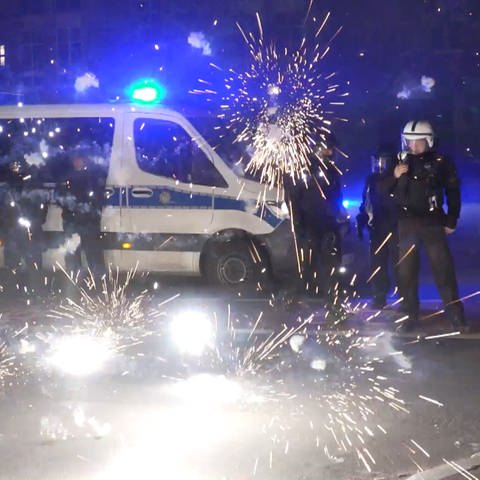 Polizeibeamte stehen hinter explodierendem Feuerwerk. Nach Angriffen auf Einsatzkräfte in der Silvesternacht hat die Diskussion um Konsequenzen begonnen. (Foto: dpa Bildfunk, picture alliance/dpa/TNN | Julius-Christian Schreiner)