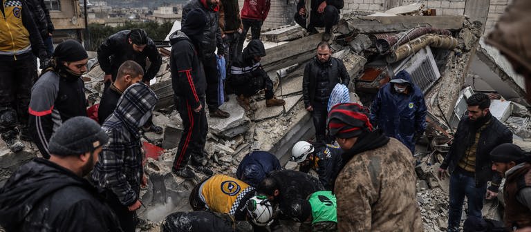 Syrische Zivilisten und Mitglieder der Weißhelme arbeiten an der Rettung von Menschen, die nach einem Erdbeben der Stärke 7,8 in Syrien unter einem zerstörten Gebäude eingeschlossen sind. (Foto: dpa Bildfunk, picture alliance/dpa | Anas Alkharboutli)