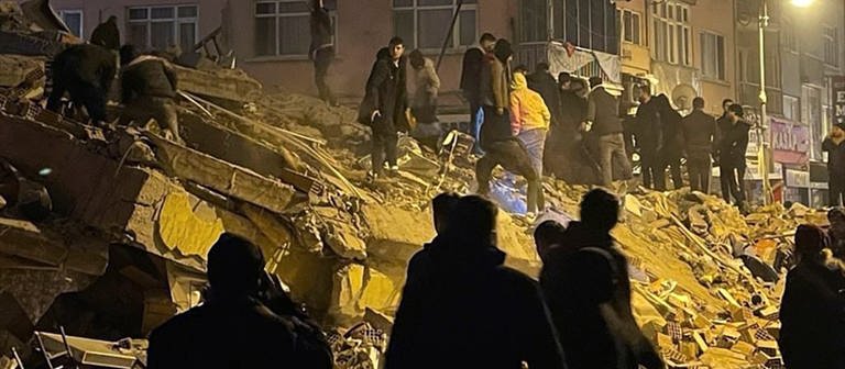 Menschen versuchen in Pazarcik in der südtürkischen Provinz Kahramanmaras, eingeschlossene Bewohner eines eingestürzten Gebäudes zu erreichen (Foto: dpa Bildfunk, picture alliance/dpa/Depo Photos/AP | Uncredited)