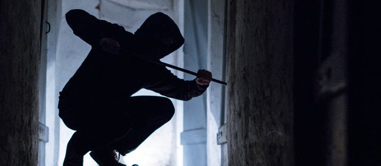 Ein "Einbrecher" hebelt mit einem Brecheisen eine Tür im Keller eines Wohnhauses auf (gestellte Szene). (Foto: dpa Bildfunk, picture alliance/dpa | Silas Stein)