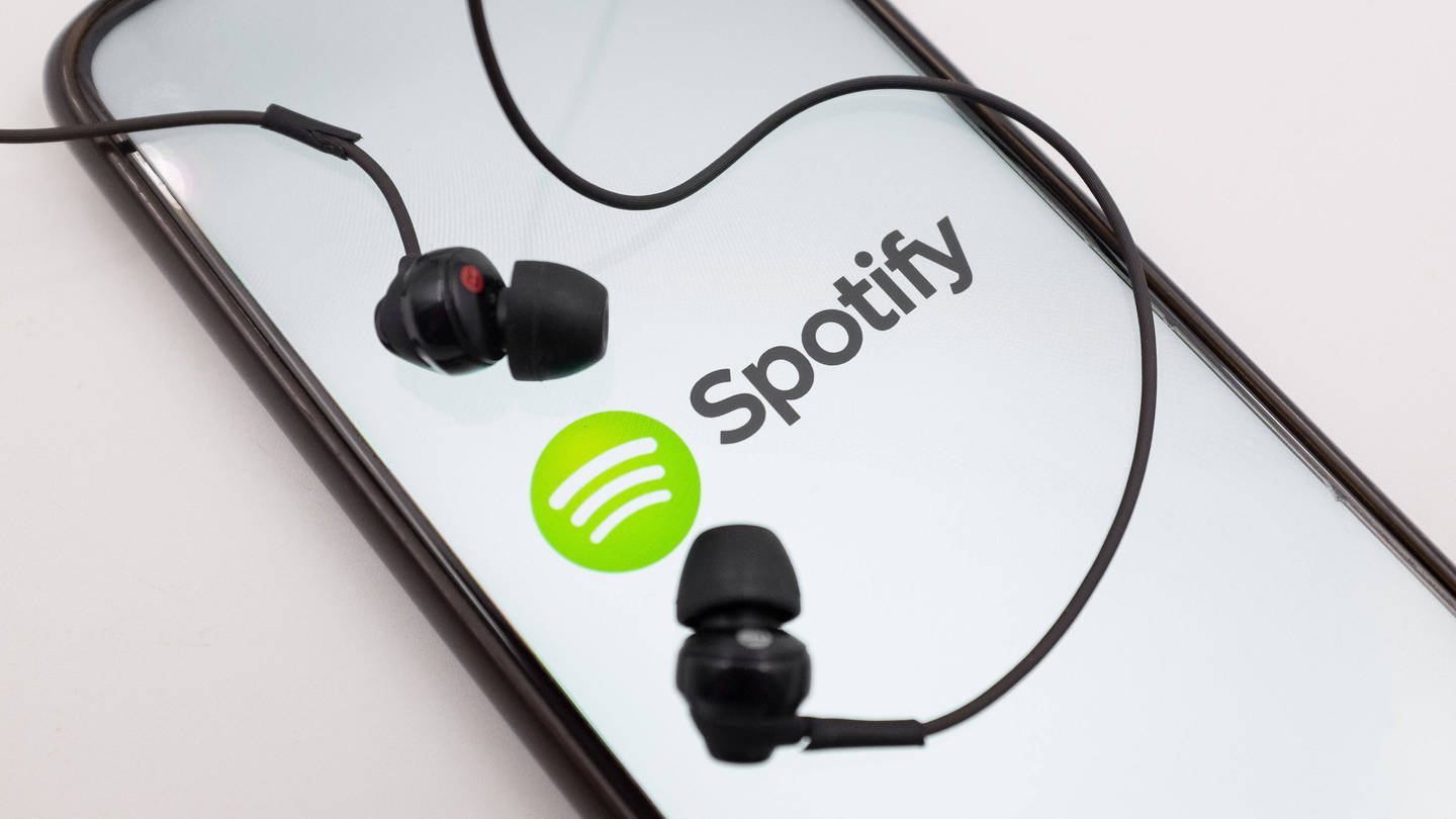 Bild Spotify-App auf dem Smartphone mit Kopfhörern (Foto: IMAGO, IMAGO / NurPhoto)