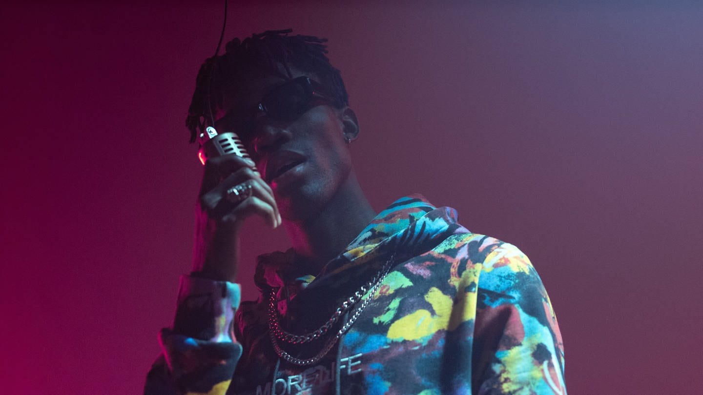 Rap-Musiker steht mit Mikrofon im Scheinwerferlicht (Foto: Pexels / cottonbro studio)