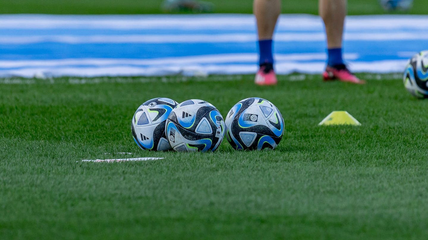 Smybolbild Fußball Frankfurt: Drei Fußbälle sind auf einem Fußballfeld zu sehen. (Foto: SWR DASDING, IMAGO / Beautiful Sports)