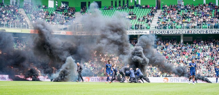 Fußball: Ehrendivision, Niederlande, Hauptrunde, 32. Spieltag, FC Groningen - Ajax Amsterdam: Fans des FC Groningen werfen während des Spiels Rauchbomben auf das Spielfeld und einige Fans, die auf das Spielfeld gelaufen sind, werden von Ordnern festgehalten. (Foto: dpa Bildfunk, picture alliance/dpa/ANP | Cor Lasker)