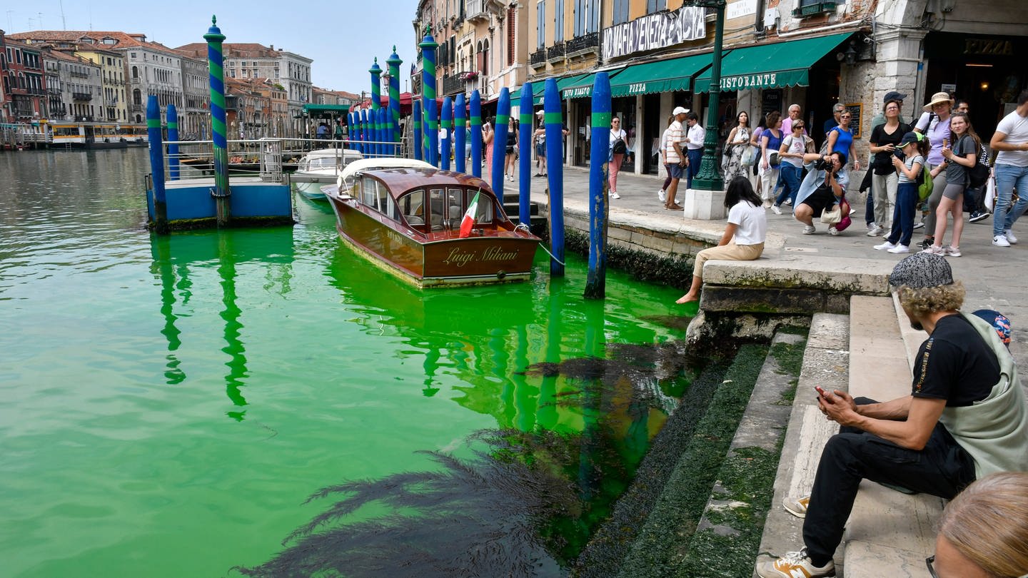 Menschen blicken auf den historischen Canal Grande in Venedig. Eine grün schimmernde Flüssigkeit im berühmten Canal Grande von Venedig hat für Aufregung in der Lagunenstadt gesorgt. Am Sonntag war das Wasser in der Nähe der Rialto-Brücke plötzlich grün. (Foto: dpa Bildfunk, picture alliance/dpa/AP | Luigi Costantini)