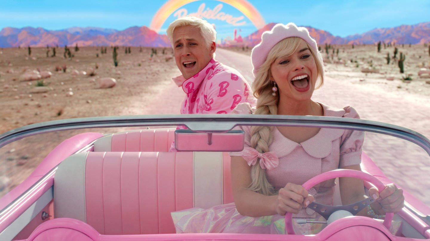 Barbie (Margot Poppie) und Ken (Ryan Gosling) fahren in einem pinken Auto. (Foto: IMAGO, Picturelux)