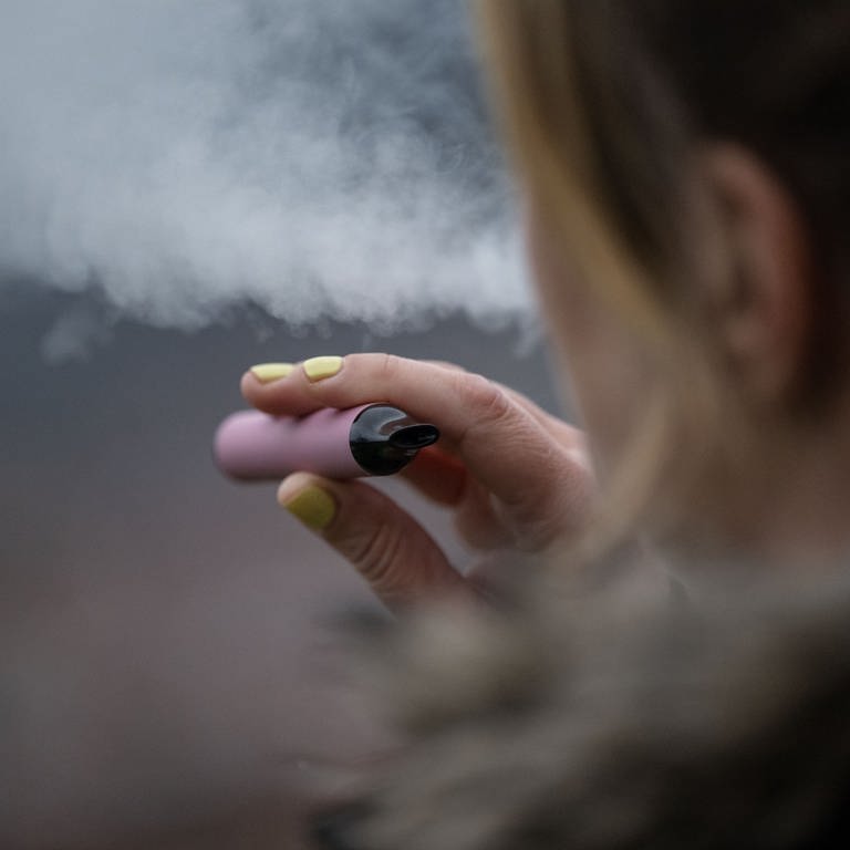 Eine junge Frau mit lackierten Fingernägeln raucht eine E-Zigarette. Der Raucheranteil von Jugendlichen in Deutschland steigt derweil. (Foto: dpa Bildfunk, picture alliance/dpa | Marijan Murat)