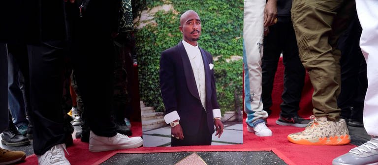 Ein Bild des verstorbenen Rappers und Schauspielers Tupac Shakur steht neben seinem Stern auf dem Hollywood Walk of Fame. (Foto: dpa Bildfunk, picture alliance/dpa/Invision/AP | Chris Pizzello)