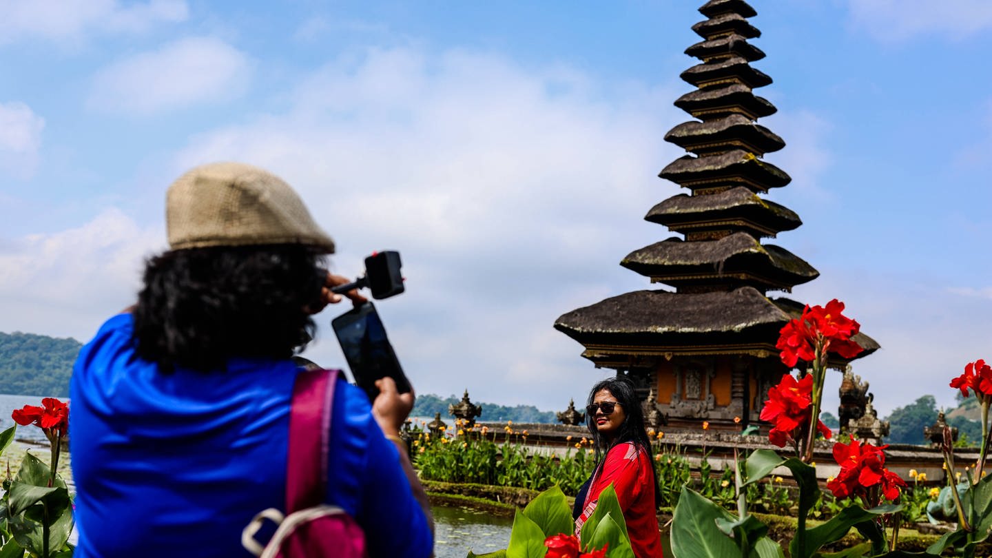 Ein Tourist macht ein Foto von einer Touristin vor einem Tempel auf Bali, Indonesien. (Foto: IMAGO, NurPhoto)