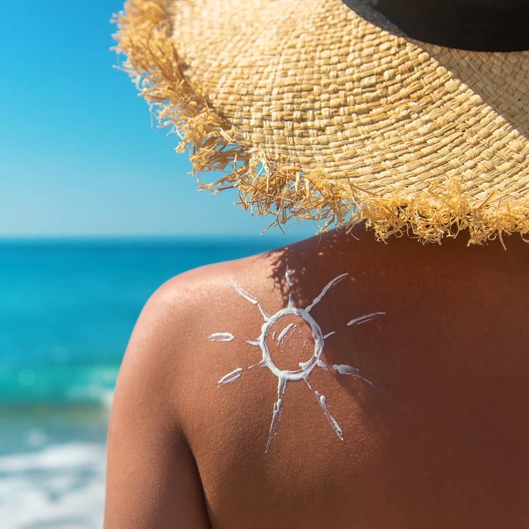 Frau mit Sonnencreme auf ihrem Rücken. In den Niederlanden können Menschen in diesem Sommer an Hunderten Orten kostenlos Sonnencreme erhalten. (Foto: IMAGO, IMAGO / Pond5)