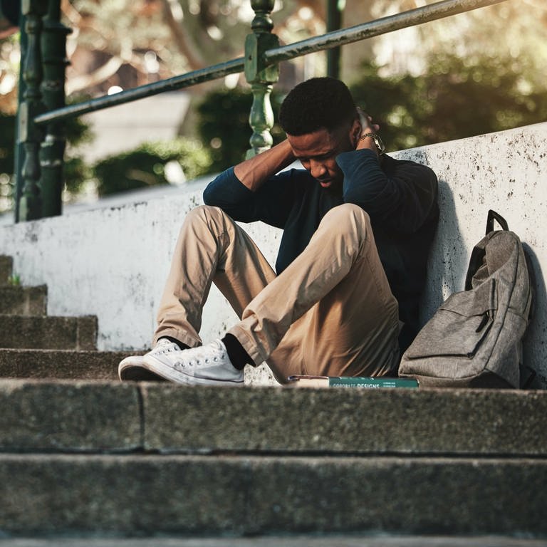 Ein Schüler mit Depressionen sitzt verzweifelt auf dem Boden. (Foto: IMAGO, Zoonar / Yuri Arcurs)