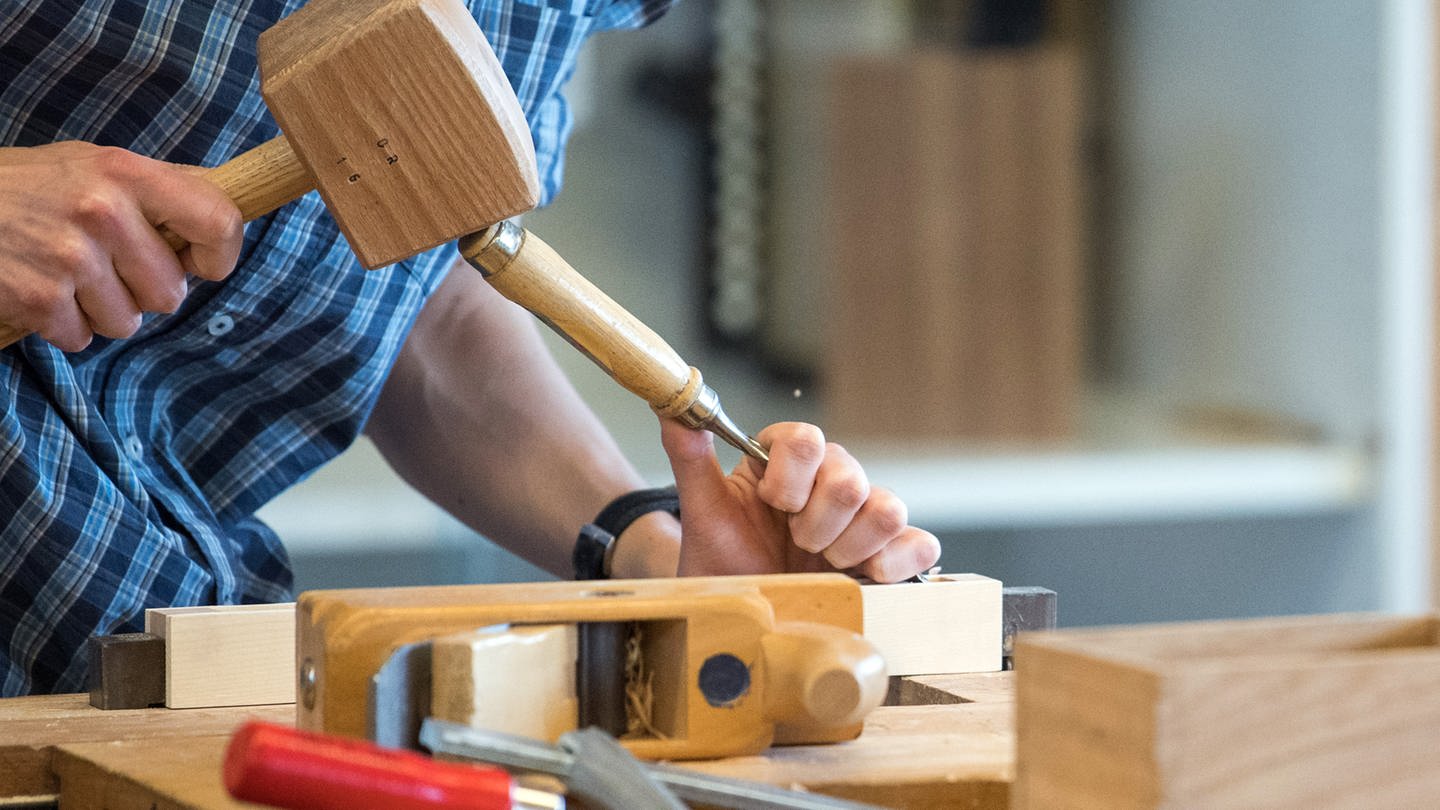 Ein Azubi im Handwerk arbeitet mit Hammer und Stechmeisel an einem Werkstück. (Foto: dpa Bildfunk, picture alliance/dpa | Sebastian Gollnow)
