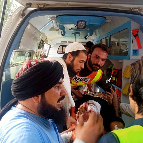 Auf diesem von der Rettungsleitstelle zur Verfügung gestellten Foto tragen Rettungskräfte einen Verwundeten nach einer Bombenexplosion zu einem Rettungswagen. (Foto: dpa Bildfunk, picture alliance/dpa/Rescue 1122 Head Quarters | Uncredited)