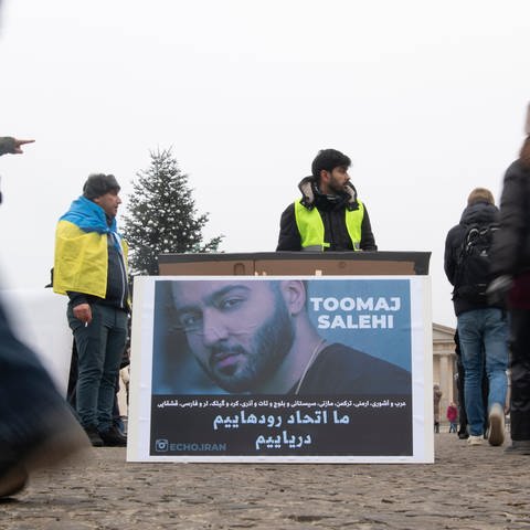 Ein großes Plakat steht bei einer Protestaktion gegen das Iran-Regime auf dem Pariser Platz. Es zeigt den iranischen Rapper Toomaj Salehi. (Foto: dpa Bildfunk, picture alliance/dpa | Paul Zinken)