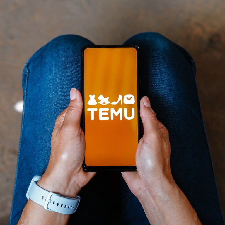Jemand hält ein Handy mit dem Logo von Temu in der Hand. (Foto: IMAGO, Zoonar)