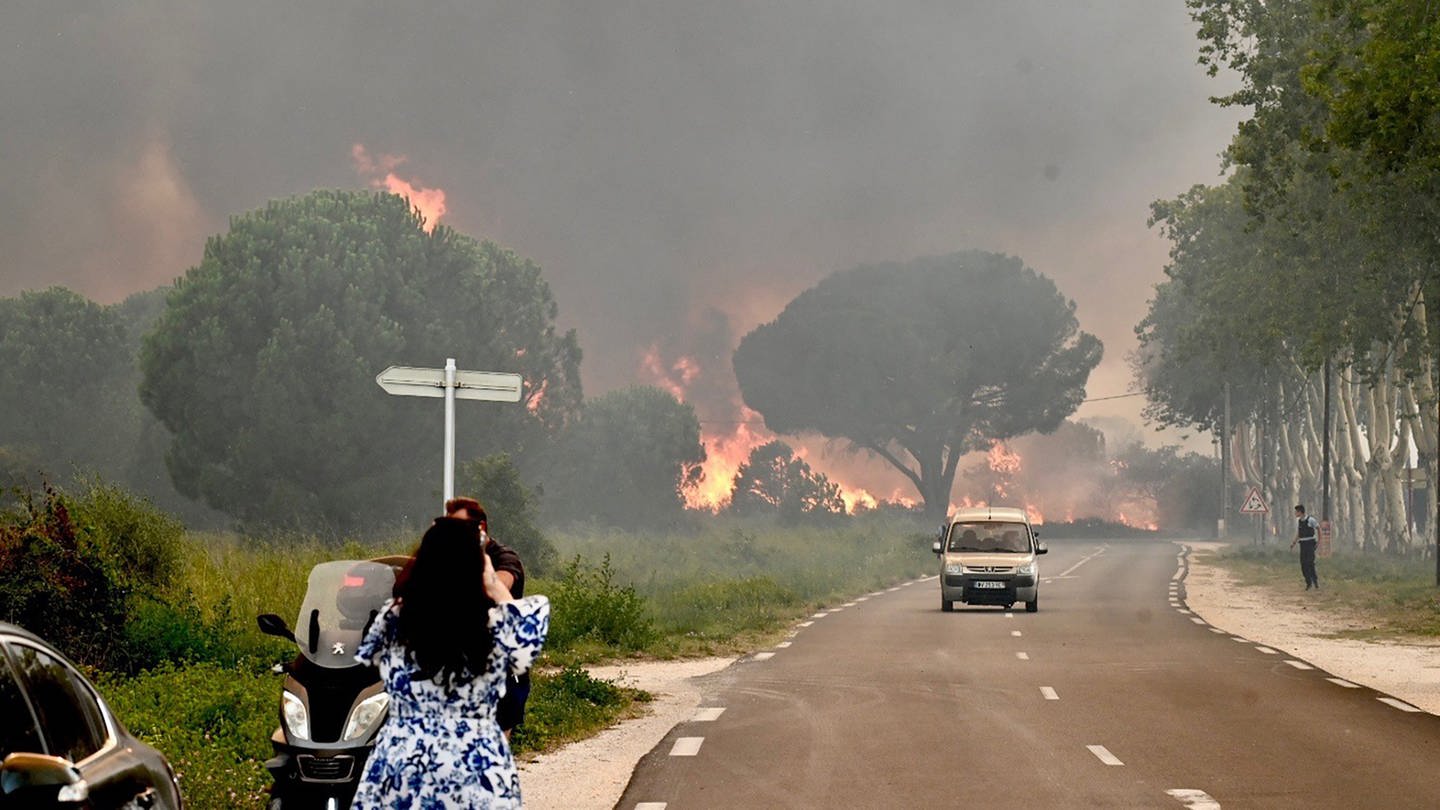 Eine Frau fotografiert in Saint-Andre in der Nähe von Argeles-sur-Mer im Südwesten Frankreichs einen Großbrand, der zur Evakuierung von rund 3000 Touristen von nahegelegenen Campingplätzen geführt hat. (Foto: dpa Bildfunk, picture alliance/dpa/AFP | Raymond Roig)