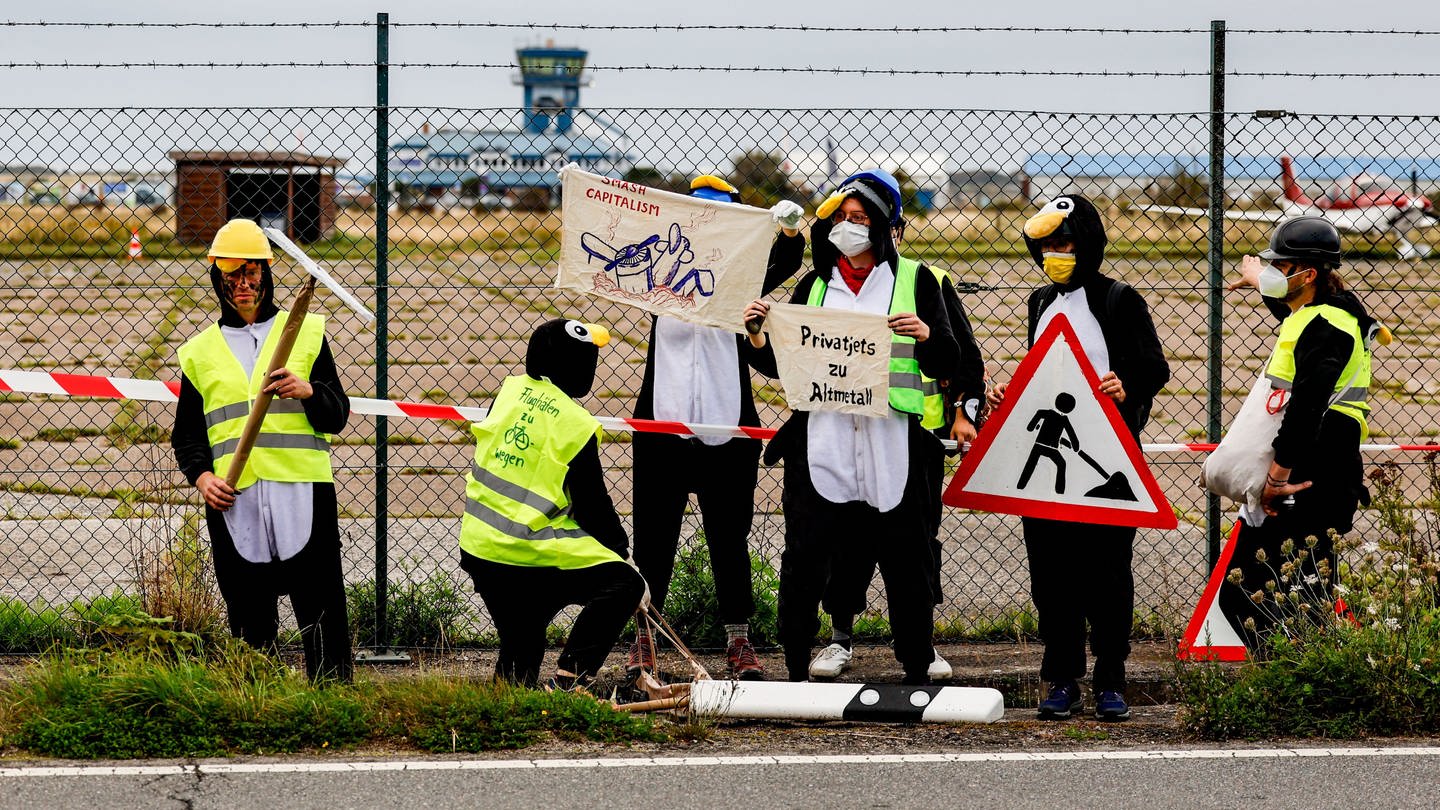Klimaaktivisten in Pinguinkostümen als Pinguin verkleidet wollen Privatjets auf Sylt am Abflug hindern (Foto: dpa Bildfunk, picture alliance/dpa | Axel Heimken)