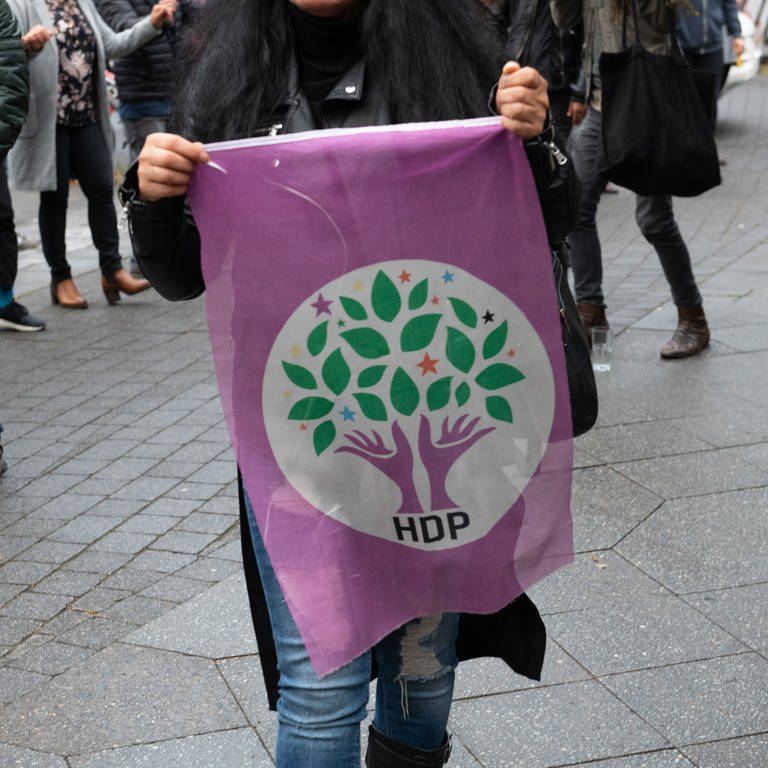 Eine Frau geht mit einer Fahne der kurdischen Partei HDP in Kreuzberg über einen Weg. (Foto: dpa Bildfunk, picture alliance/dpa | Paul Zinken)