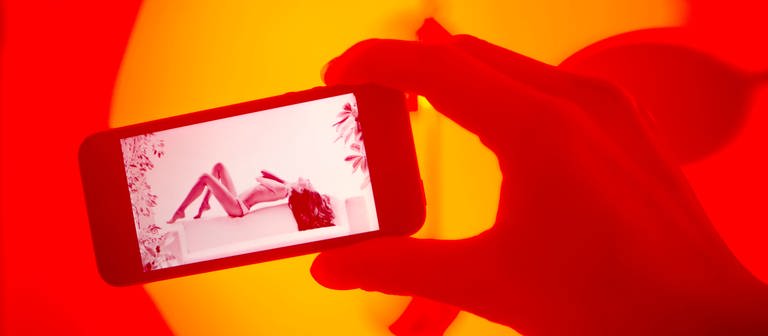 Eine Person guckt sich pornografisches Material auf einem Smartphone an. (Foto: IMAGO, Elmar Gubisch)