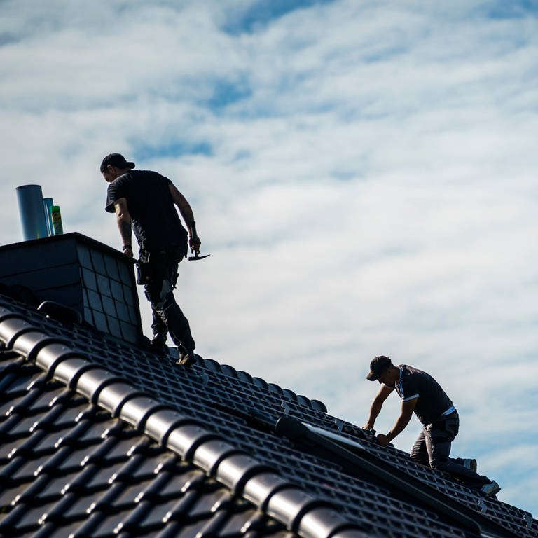 Zwei Dachdecker arbeiten auf einem Dach. (Foto: dpa Bildfunk, picture alliance/dpa | Andreas Arnold)