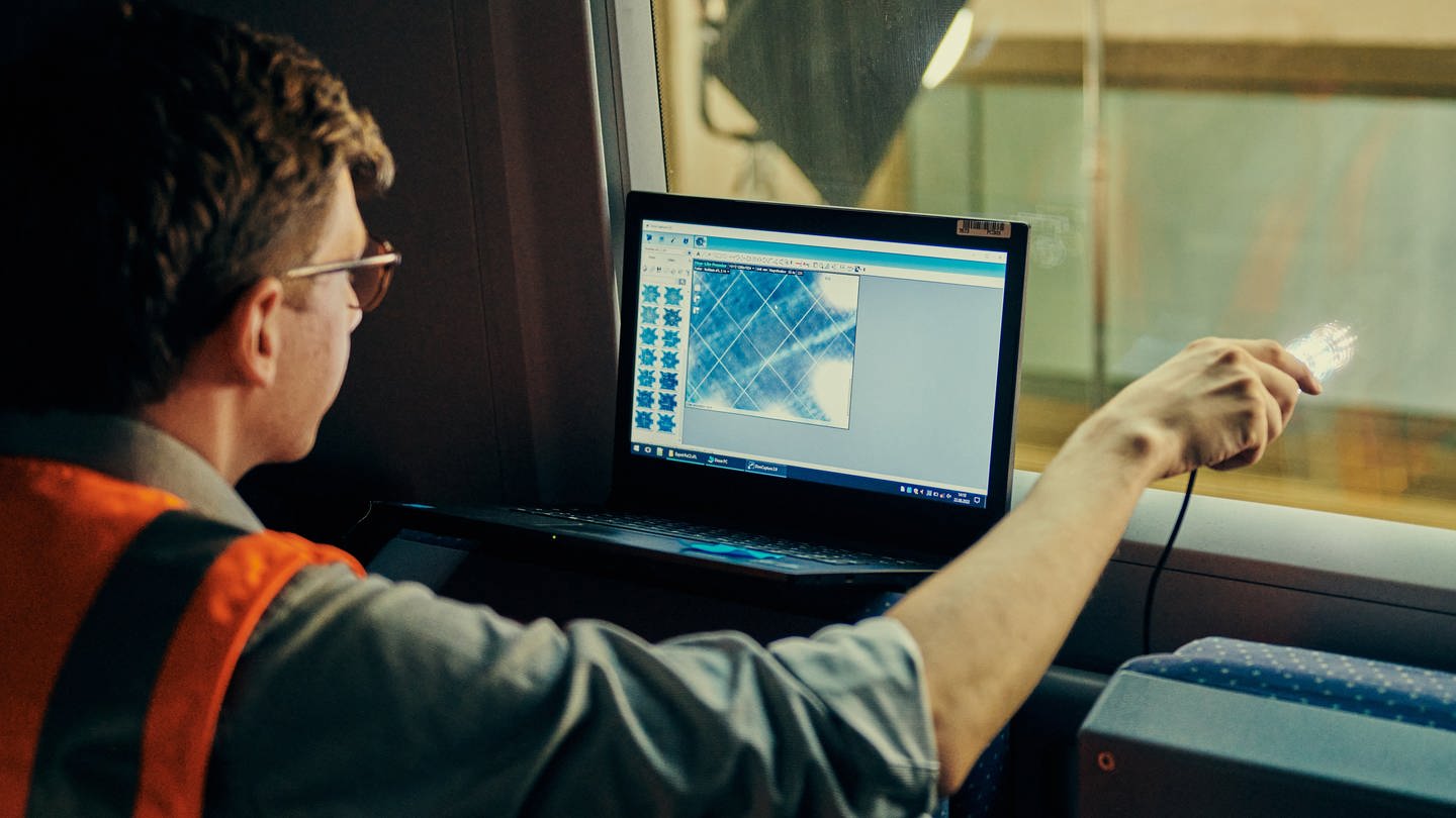 Ein Mitarbeiter der Deutschen Bahn lasert eine Scheibe, um den Mobilfunk im Zug zu verbessern. (Foto: Deutsche Bahn AG / Dominic Dupont)