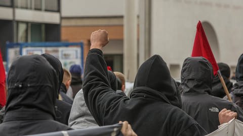 Symbolbild: Rechtsextreme in Deutschland. Es sind Menschen mit Kapuze zu sehen, einer von ihnen hebt die Faust in die Luft. (Foto: IMAGO, IMAGO / Moritz Schlenk)