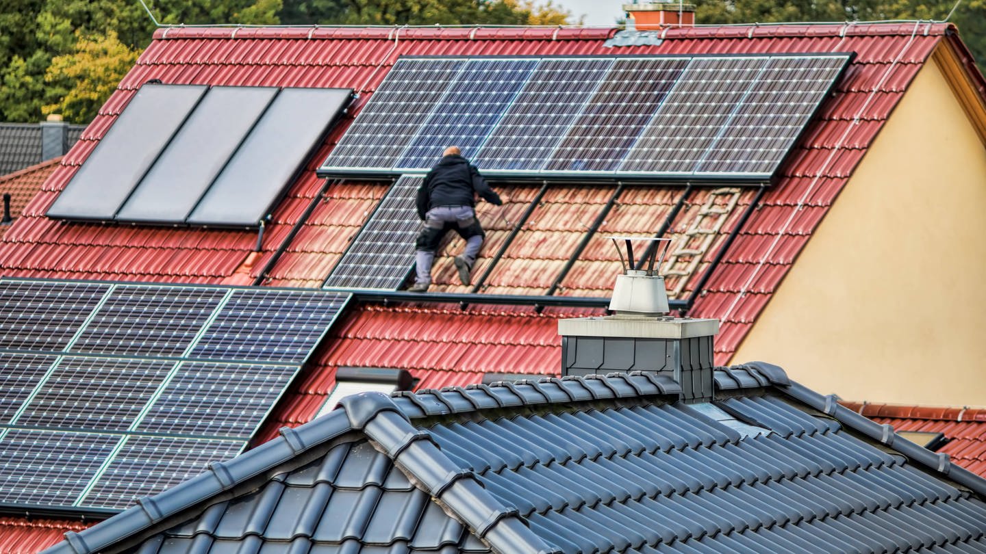 Ein Mann montiert eine Solaranlage auf einem Dach (Foto: IMAGO, IMAGO / Zoonar)