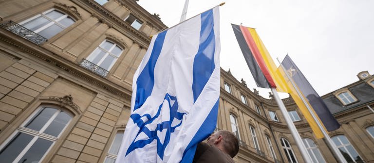Die Flagge Israels wird von einem Mitarbeiter des Staatsministeriums Baden-Württemberg zwischen den Flaggen der EU, Deutschlands und Baden-Württembergs gehisst. (Foto: dpa Bildfunk, picture alliance/dpa | Marijan Murat)