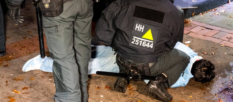 Eine Person liegt während Ausschreitungen von der Polizei fixiert auf dem Boden. In der Halloween-Nacht ist es in Hamburg zu Ausschreitungen gekommen. (Foto: dpa Bildfunk, picture alliance/dpa | Daniel Bockwoldt)