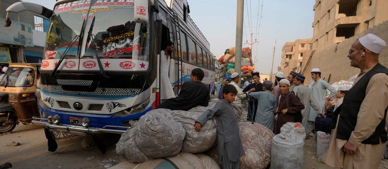 Afghanische Familien warten darauf, in Busse einzusteigen, die sie in ihr Heimatland bringen sollen. UN-Organisationen berichten von einem starken Anstieg der Zahl der Afghanen, die in ihre Heimat zurückkehren, seit Pakistan ein hartes Durchgreifen gegen illegal im Land lebende Menschen eingeleitet hat. (Foto: dpa Bildfunk, picture alliance/dpa/AP | Fareed Khan)