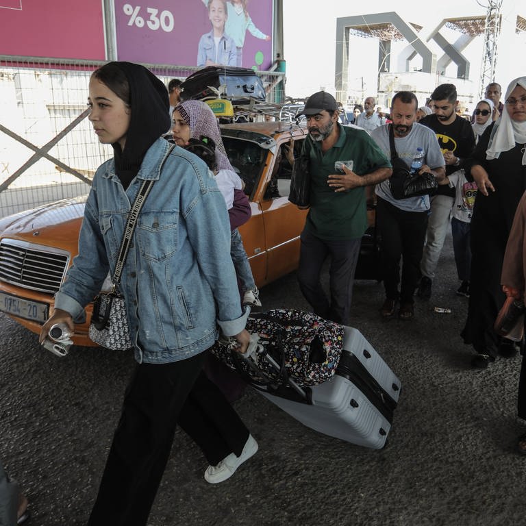 Palästinenser tragen Gepäck am Grenzübergang zwischen dem Gazastreifen und Ägypten. Verletzte Palästinenser und Inhaber ausländischer Pässe können über den Grenzübergang Rafah evakuiert werden. (Foto: dpa Bildfunk, picture alliance/dpa | Abed Rahim Khatib)