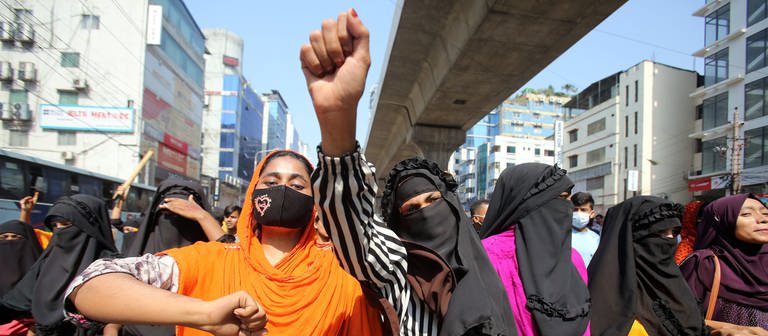 Bei einer Demonstration von Textilarbeitern und Arbeiterinnen reckt eine Frau ihre Faust in die Luft. In Bangladesch haben Tausende Beschäftigte der Textilbranche für eine bessere Bezahlung ihrer Arbeit protestiert. Es kam zu Zusammenstößen mit der Polizei. (Foto: dpa Bildfunk, picture alliance/dpa/ZUMA Press Wire | Habibur Rahman)