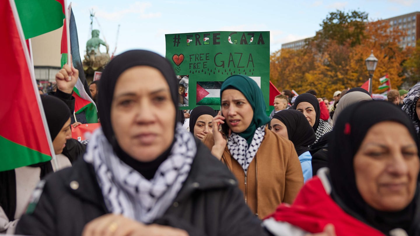 Teilnehmer einer Pro-Palästina-Kundgebung am Neptunbrunnen in Berlin halten ein Plakat mit der Aufschrift „Free Palestine