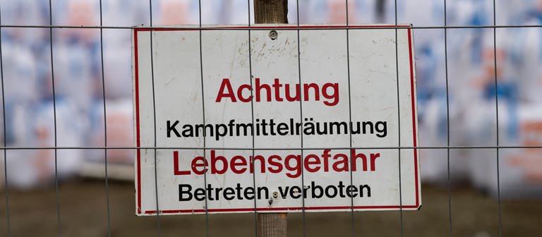 Ein Schild "Achtung Kampfmittelräumung. Lebensgefahr. Betreten verboten" ist hinter einer Absperrung am vermutlichen Fundort einer Weltkriegsbombe zu sehen. (Symbolbild) (Foto: SWR DASDING, picture alliance/dpa | Swen Pförtner)