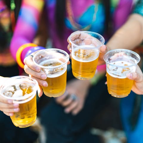 Junge Menschen mit Plastik-Bierbechern stoßen an. Alkoholkonsum und Alkoholvergiftungen bei Jugendlichen geht weiter zurück. (Foto: IMAGO, IMAGO / Zoonar)