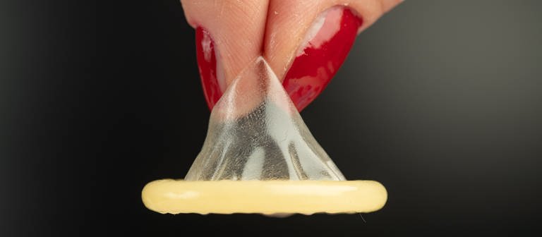 Ein Kondom wird mit zwei Fingern gehalten. (Foto: dpa Bildfunk, Friso Gentsch)