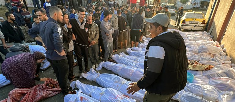 Palästinenser untersuchen die Leichen von Menschen, die bei israelischen Luftangriffen auf das Flüchtlingslager Dschabalia getötet wurden. (Foto: dpa Bildfunk, picture alliance/dpa/AP | Ahmed Alarini)
