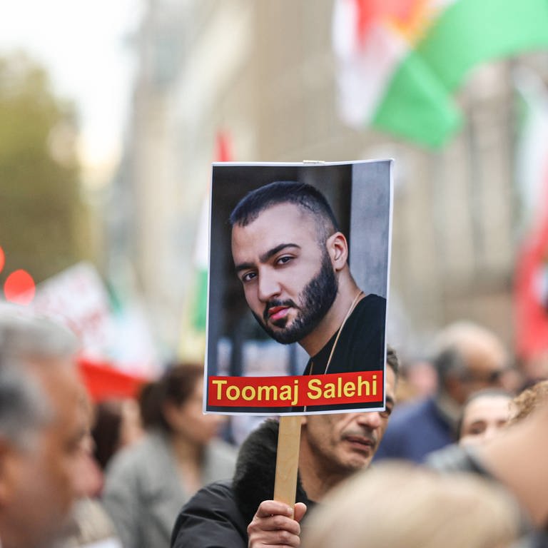 Plakat mit einem Bild von Toomag Salehi bei einer Demo in Köln. Der Rapper soll jetzt auf Kaution frei sein. (Foto: IMAGO, IMAGO / aal.photo)